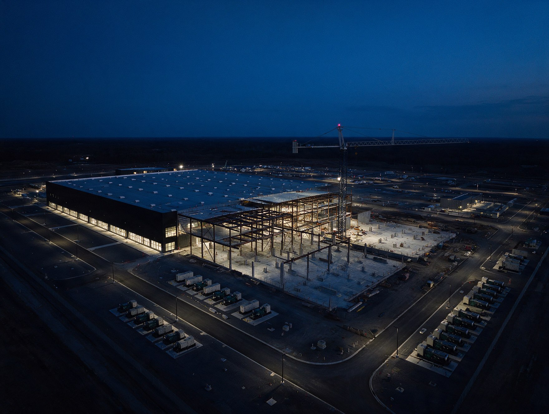 Data center campus at dusk with one finished hall and the next phase under construction