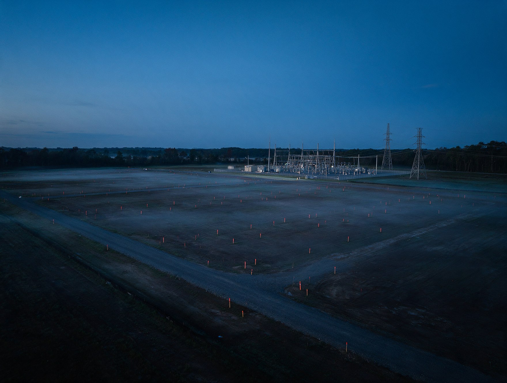 Greenfield data center site at dawn beside a high-voltage substation